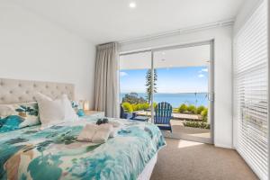 - une chambre avec un lit et une vue sur l'océan dans l'établissement Maraetai Couples Retreat - Omana Beach Apartment, à Auckland