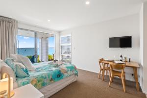 Schlafzimmer mit einem Bett, einem Schreibtisch und einem Fenster in der Unterkunft Maraetai Couples Retreat - Omana Beach Apartment in Auckland