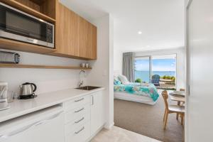 a kitchen with a microwave and a dining room at Maraetai Couples Retreat - Omana Beach Apartment in Auckland