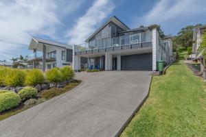 une grande maison avec une allée en face de celle-ci dans l'établissement Maraetai Couples Retreat - Omana Beach Apartment, à Auckland