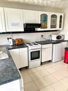 a kitchen with white appliances and white cabinets at 3 bedroom peaceful house (5 people maximum) in Morriston