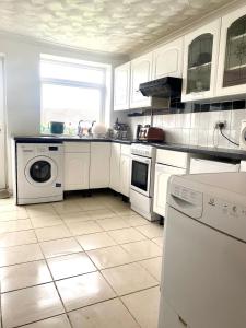 uma cozinha com electrodomésticos brancos e piso em azulejo em 3 bedroom peaceful house (5 people maximum) em Morriston