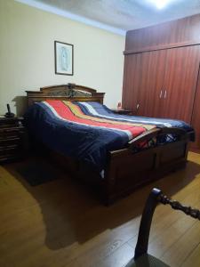 1 cama grande en un dormitorio con pared de madera en Recidencia El Hogar, en Cochabamba