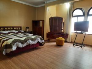 a bedroom with a bed and a flat screen tv at Recidencia El Hogar in Cochabamba