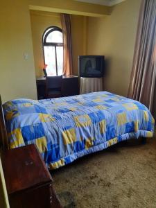Un dormitorio con una cama azul y amarilla y una ventana en Recidencia El Hogar, en Cochabamba