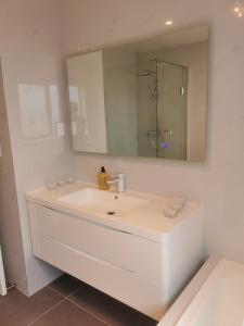 ein weißes Badezimmer mit einem Waschbecken und einem Spiegel in der Unterkunft Lovely House in Central Papatoetoe in Auckland