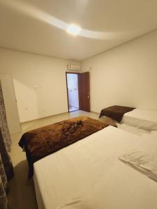 um quarto com duas camas brancas e uma porta em Casa Sunstay Garden com piscina em Bombinhas