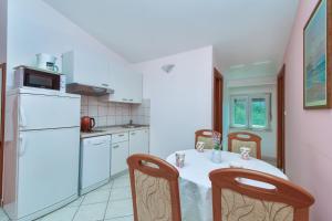 a kitchen with a table and a white refrigerator at Apartments by the sea Pisak, Omis - 10323 in Pisak