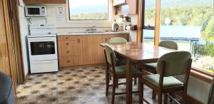 eine Küche mit einem Tisch und Stühlen sowie einem Fenster in der Unterkunft Glendale River View in Manapouri