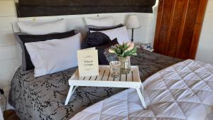 Una cama con una mesa con un jarrón de flores. en Wharfe Cottage, en Wellsford