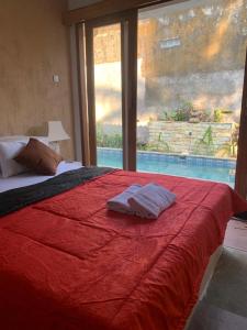 1 dormitorio con cama roja y ventana grande en Pranajaya loka private villa, en Tejakula
