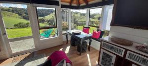 a room with a desk and windows with a view at Wharfe Cottage in Wellsford