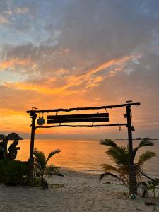 a bench on the beach with a sunset in the background at Redang Campstay in Redang Island