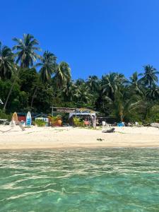 a beach with palm trees and the water at Redang Campstay in Redang Island