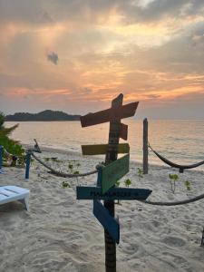 a wooden sign on a beach with the ocean at Redang Campstay in Redang Island
