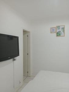 Une télévision à écran plat est installée au-dessus d'un mur blanc. dans l'établissement Suítes Paraty, à Parati
