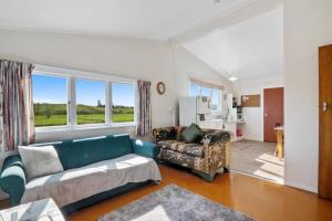 Upper MoutereにあるOrchard Flat - Mapua Holiday Unitのリビングルーム(青いソファ、椅子付)