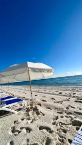 a white umbrella and chairs on a beach at Monte Carlo Suites in Miami Beach in Miami Beach