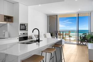 a white kitchen with a view of the ocean at Wave Watcher's Delight at Acqua Palm Beach in Gold Coast