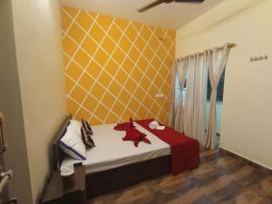 a bedroom with a bed and a yellow wall at Arangan kudil in Srīrangam