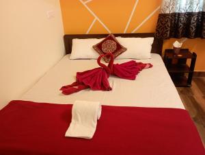 a bedroom with a bed with red and white sheets at Arangan kudil in Srīrangam +19 photos