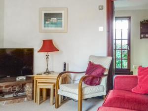 sala de estar con sofá, silla y TV en Kays Cottage, en Buckfastleigh