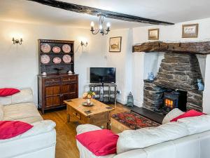 a living room with two couches and a stone fireplace at Fedwr Gog Cottage in Llangwm