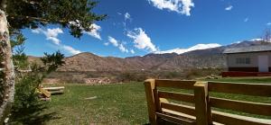 a bench in a field with mountains in the background at Esencia Cabaña in Potrerillos