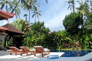 チャンディダサにあるVilla Hanoman Candidasa - 3 Bedrooms With Private Poolのスイミングプールの横に座る椅子