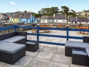 a patio with wicker chairs and tables and a blue railing at Wylandre in Amlwch