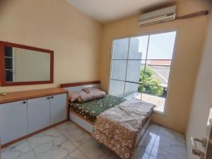 a bedroom with a bed and a large window at Mulia Homestay Pasuruan 