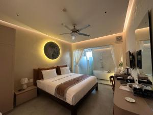 a bedroom with a bed and a desk with a ceiling fan at Phuong Nam Hotel An Giang in Long Xuyên