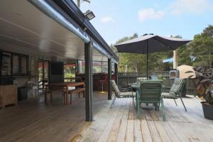 een patio met een tafel en stoelen en een parasol bij Tui Lodge Oakura 