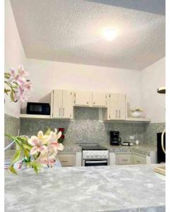 una cocina con armarios blancos y flores rosas en una encimera en Departamento familiar Sweet Home, en Reynosa