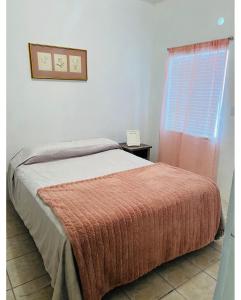ein Schlafzimmer mit einem Bett mit einer orangefarbenen Decke und einem Fenster in der Unterkunft Departamento familiar Sweet Home in Reynosa