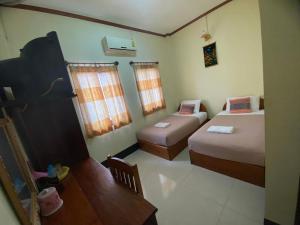 a small room with two beds and a table at A Tee Guesthouse in Luang Prabang