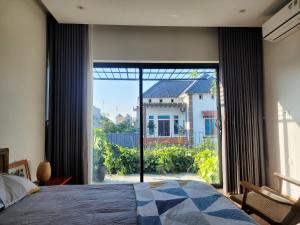 a bedroom with a large window with a view of a house at Noi Bai Flight Path Homestay in Hanoi