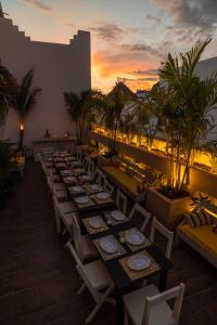 una fila de mesas y sillas en un balcón con vistas a la puesta de sol en Gardenia Collective en Tulum