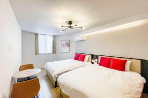 Dos camas con almohadas rojas en una habitación. en SEED Tanimachi 6-chome, en Osaka