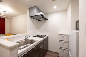 a small kitchen with a sink and a microwave at Wellsquareism Otsuka in Tokyo