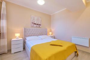 a bedroom with a large bed with a yellow blanket at Apartments with a parking space Mali Losinj (Losinj) - 15201 in Mali Lošinj