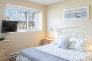 a bedroom with a bed and a television and a window at Breezy Beach Villa near the Lake in Penticton