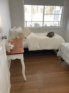 a bed in a room with a table and a window at Clarendon Cottage , near lowood in Clarendon