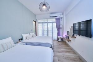 a hotel room with two beds and a flat screen tv at HiHi Skylight in Hengchun