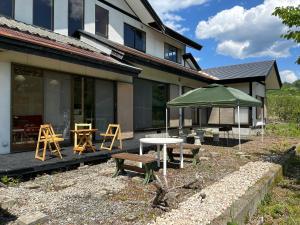 a patio with two tables and a green umbrella at Cool-Villa 飛騨リゾート in Hida