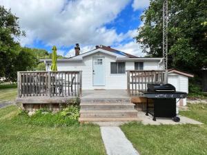 a house with a porch and a grill in the yard at Relaxing Riverside Getaway with a Cozy Fireplace in Bancroft