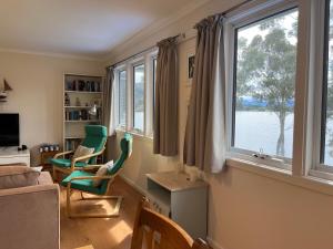 a living room with two green chairs and a window at Anchorage Waterfront Retreat in Castle Forbes Bay