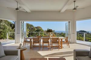 Un comedor con mesa y sillas y ventanas. en The Cape Retreat, en Cape Schanck