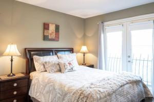 a bedroom with a bed and two lamps and a window at Sun & Sails Villa by the Beach in Penticton
