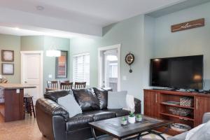 a living room with a leather couch and a flat screen tv at Sun & Sails Villa by the Beach in Penticton